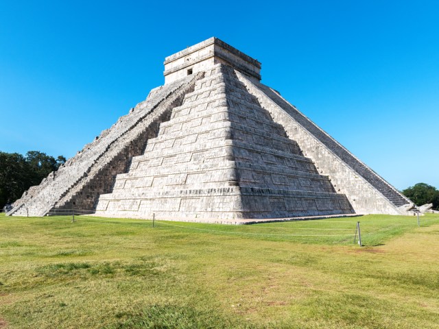 Temple of Kukulcán standing in grassy field in Chichén Itzá, Mexico