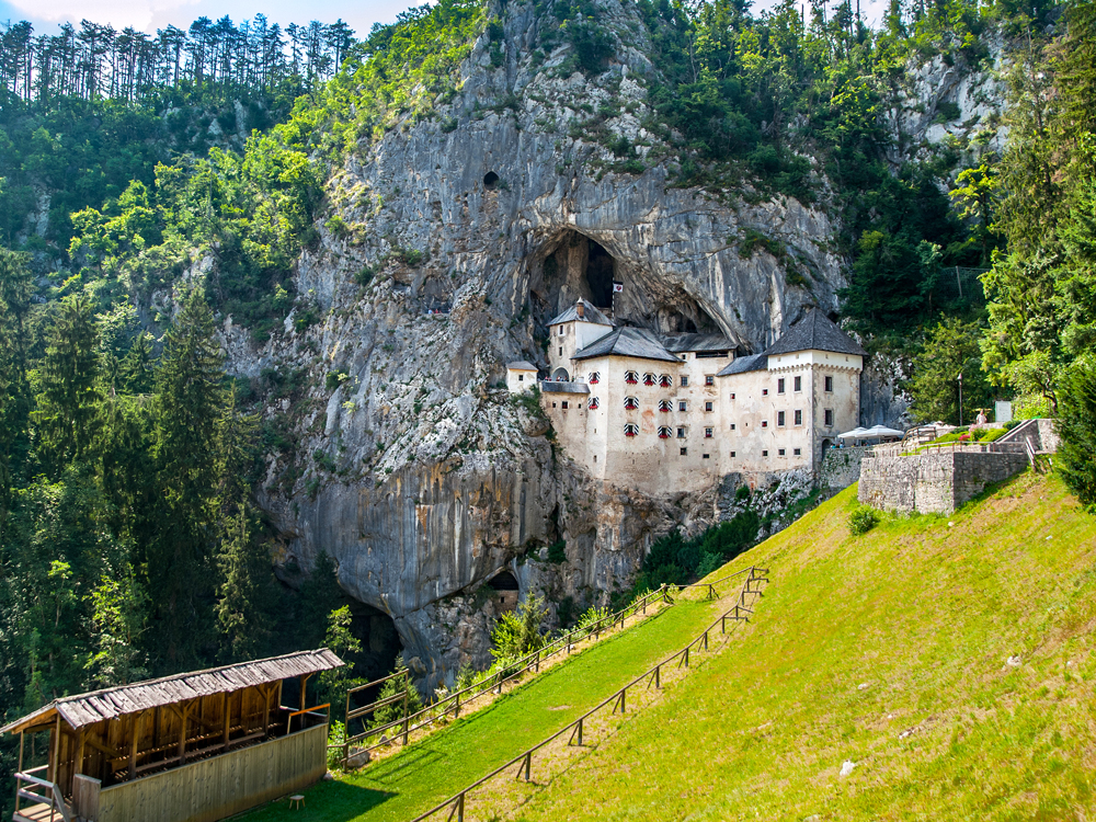 Predjama Castle built into cave on steep grassy hill in Slovenia