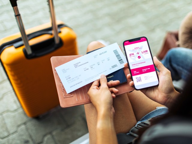 Traveler holding boarding pass, passport, and ticket on cellphone