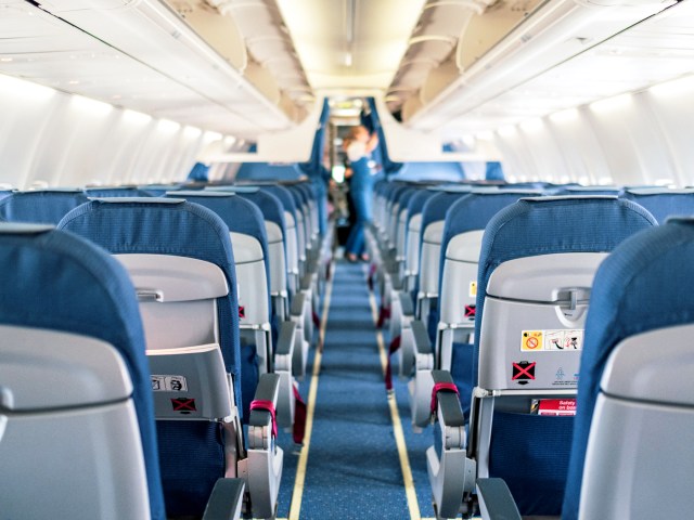 View of single-aisle aircraft cabin from back to front