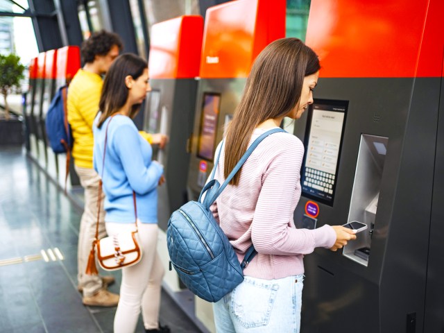 People using ticket machines at train station