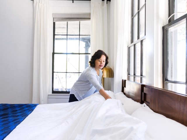 Housekeeper making bed in hotel room