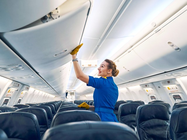 Flight attendant closing overhead bin on airplane