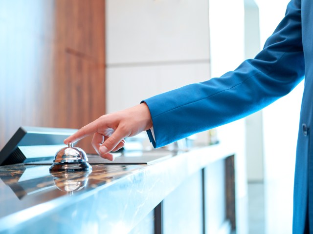 Person ringing bell at hotel front desk