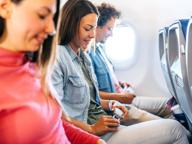 Passengers fastening seatbelts in airplane row