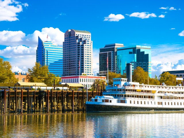 Riverboat docked on Sacramento River with high-rise buildings behind