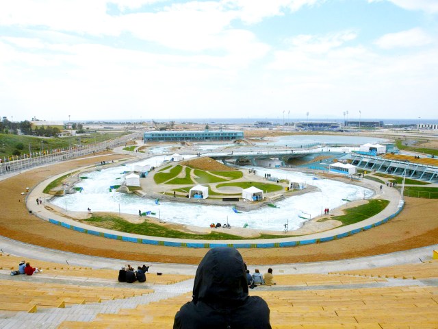 Scattered people sitting in stands of abandoned Hellinikon Olympic Canoe and Kayak Slalom Centre in Athens, Greece