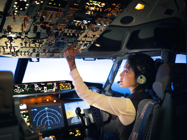 Pilot adjusting instruments in aircraft cockpit