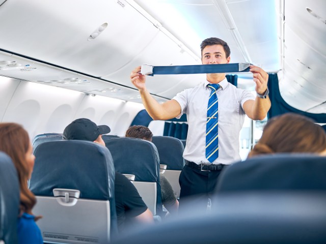 Flight attendant performing safety demonstration in aircraft aisle