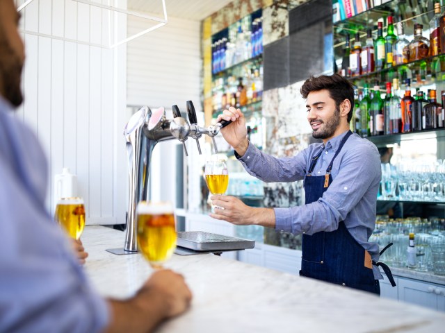 Bartender pouring beer from tap at hotel bar