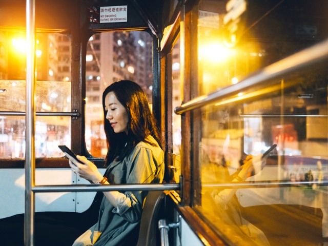 Woman using phone while riding streetcar