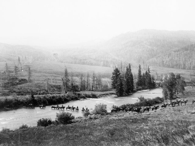 Historic photo of group of people on horseback crossing river in Yellowstone National Park