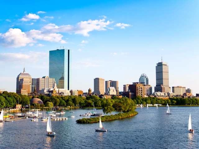 Aerial view of sailboats in Boston Harbor with skyline in background