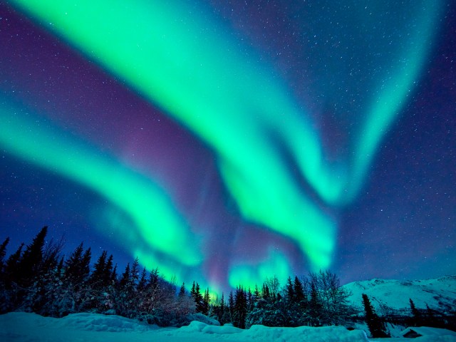 Northern lights over snowy Alaska landscape at night