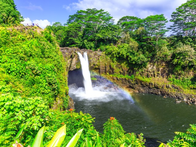 Waterfall and rainbow over small natural pool in Hawaii