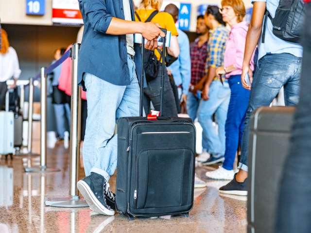 Passengers standing in airport queue with luggage