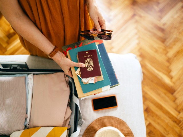 Traveler packing passport and other items into suitcase