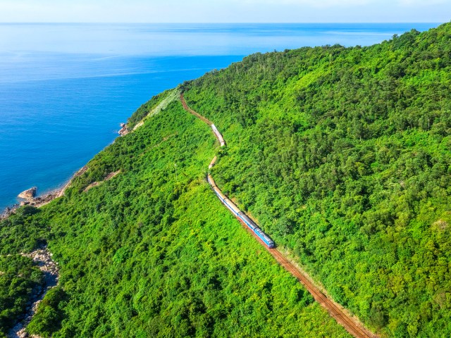 Aerial view of Reunification Express on lush hillside overlooking sea in Vietnam