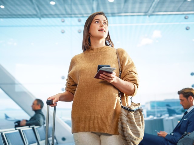 Traveler in airport holding phone and luggage