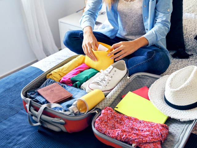 Traveler packing suitcase on bed