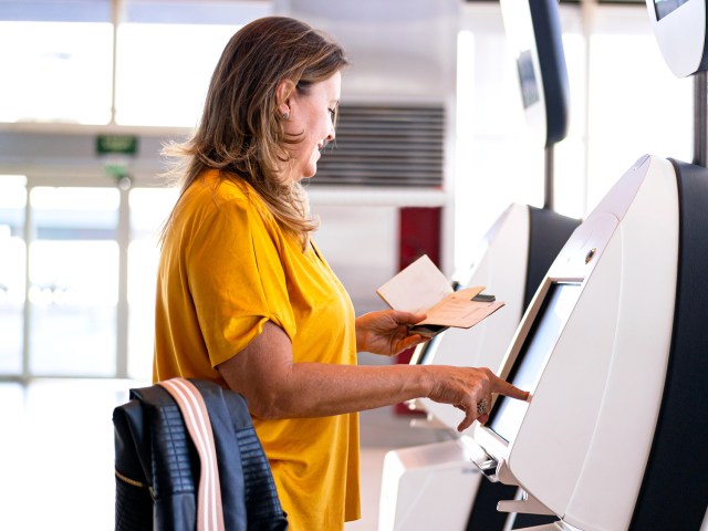 Airline passenger using electronic check-in kiosk