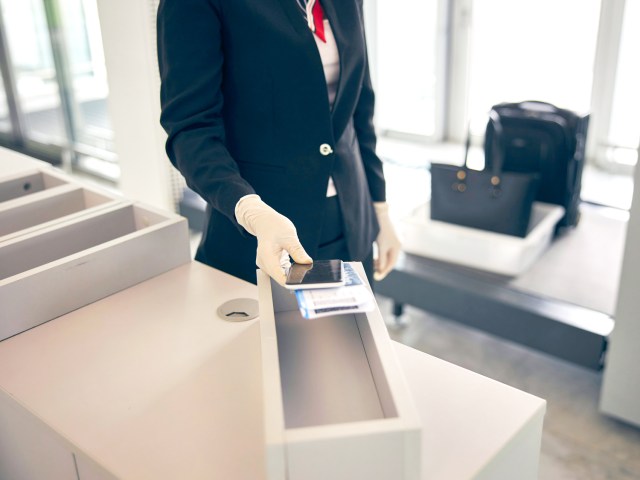 Airline passenger holding phone and boarding pass at airport