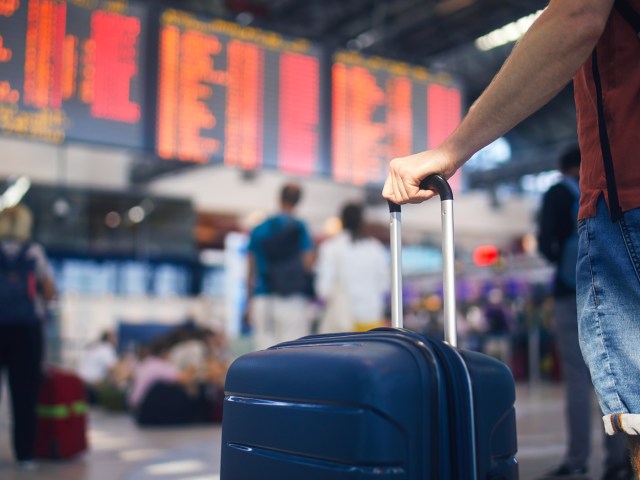 Close-up image of traveler holding luggage handle in airport