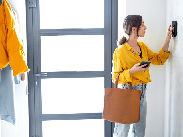 Woman setting house alarm system