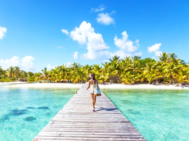 Woman walking on pier to tropical island