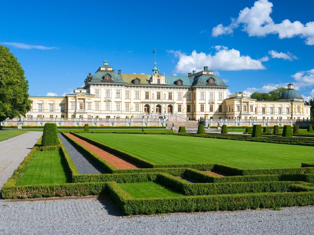 Manicured gardens in front of grand exterior of Sweden's Drottningholm Palace