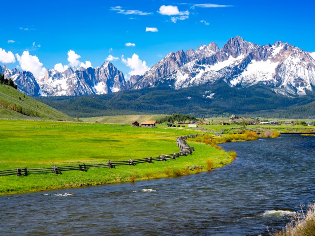 Winding river alongside farm and snow-capped mountains in Idaho