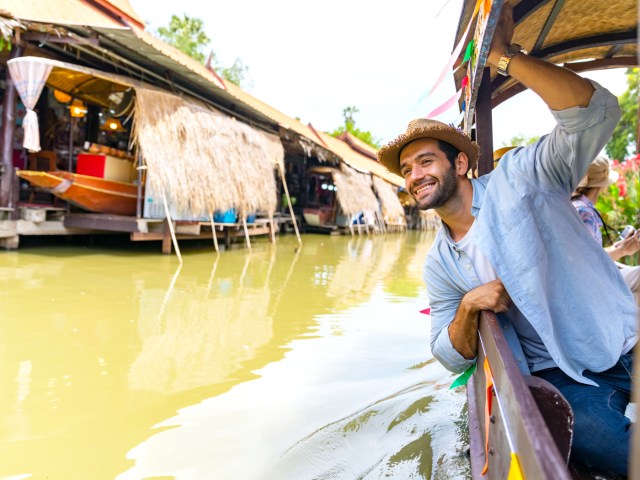 Man leaning over boat to lout out over canal