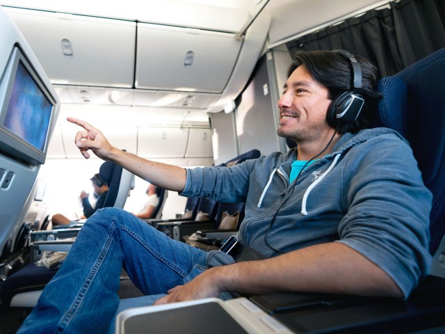 Airline passenger using touchscreen entertainment screen on seatback