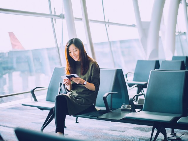 Airline passenger looking at boarding pass while sitting in gate area