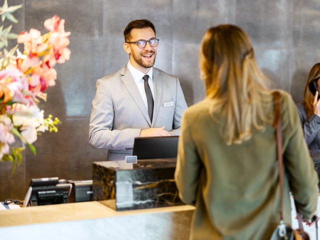 Front desk receptionist speaking to hotel guest