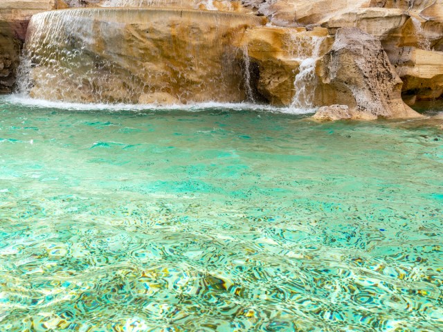 Close-up view of coins at bottom of Trevi Fountain in Rome, Italy