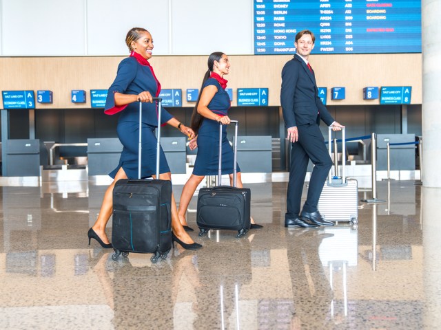 Flight attendants walking through airport check-in lobby with their luggage