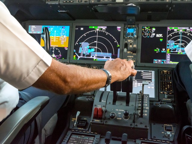 Close-up image of airline pilot using cockpit controls