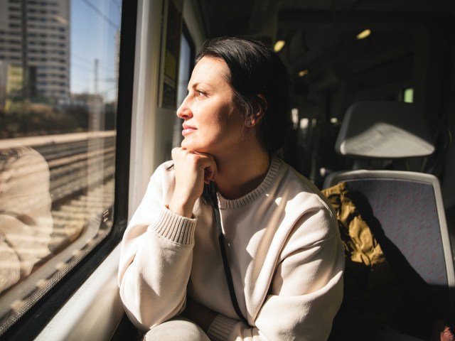 Woman in sweater looking out train window