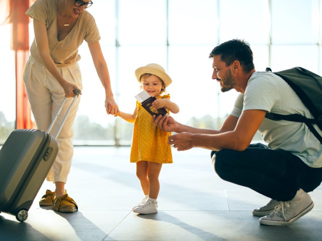 Mother and father showing passport to toddler in airport