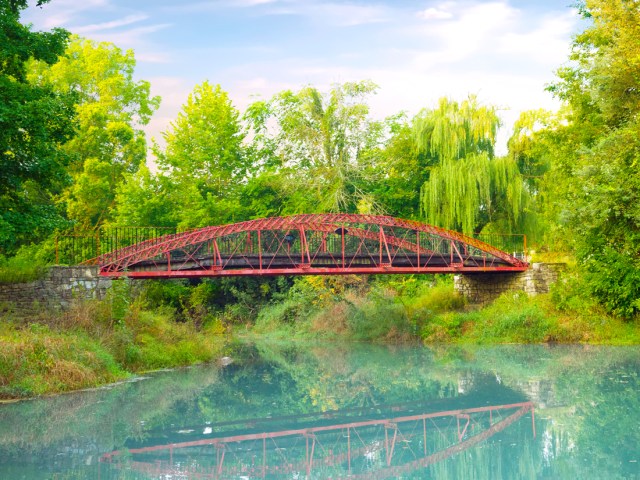 Red bridge over river with reflection of trees in Delphi, Indiana