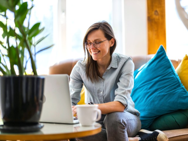 Woman sitting on couch using laptop computer