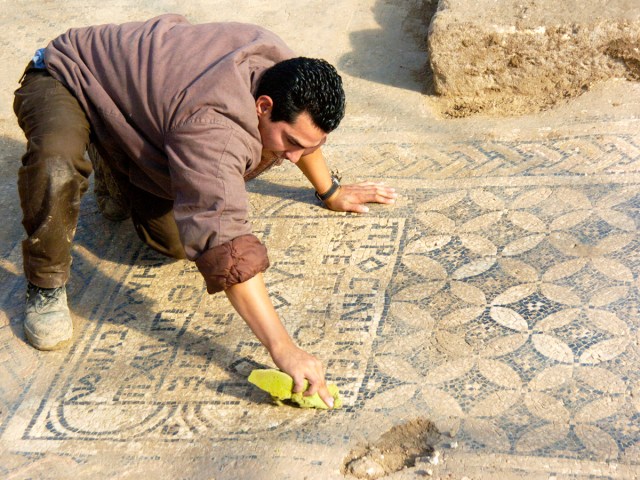 Worker cleaning mosaic at Megiddo Church in Israel