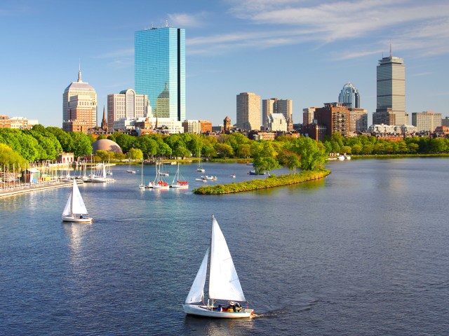 Aerial view of sailboats in Boston Harbor with skyline in background