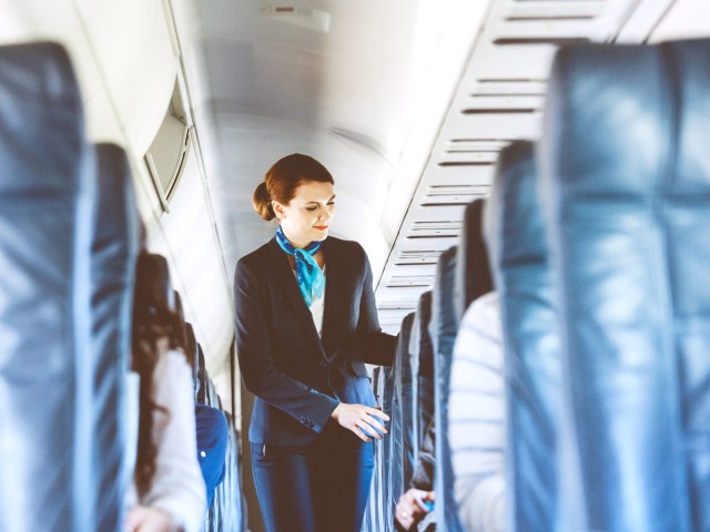 Flight attendant walking down aisle checking seats