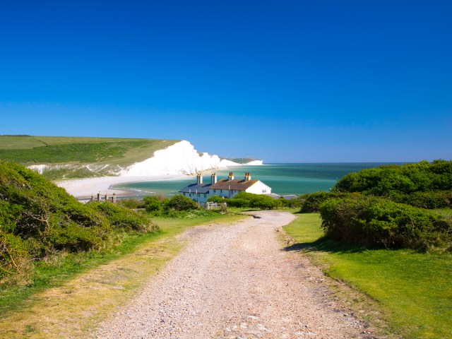 Dirt road leading to home beside white cliffs in Seaford, England