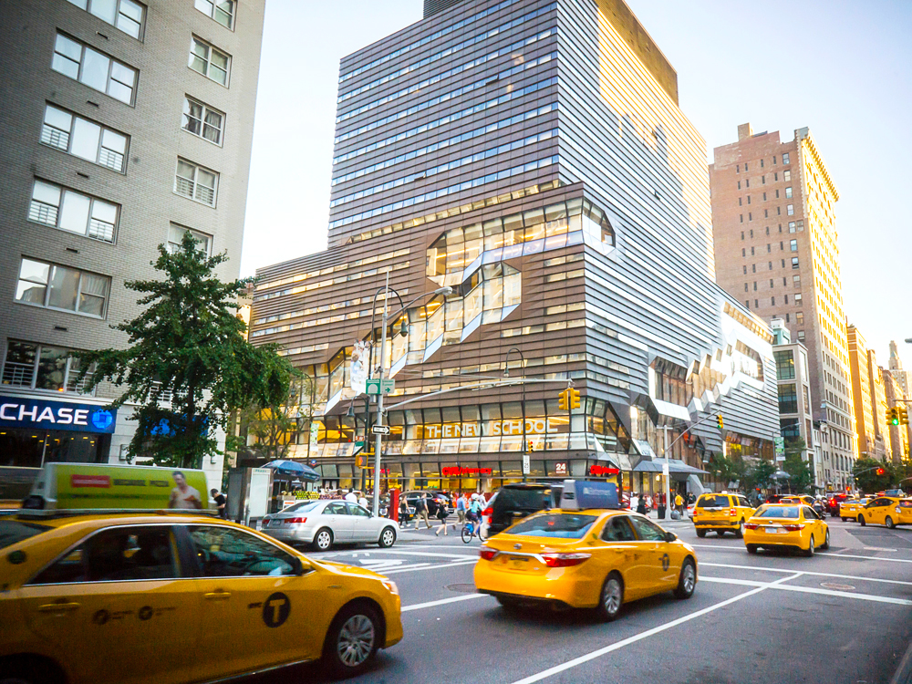 Yellow taxi cabs driving by the New School in Manhattan, New York City