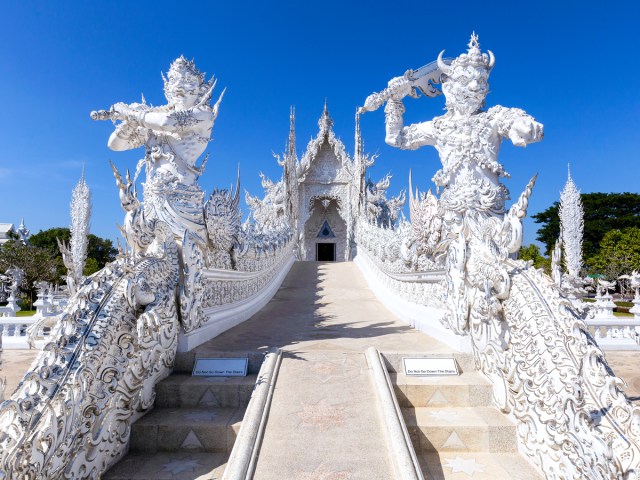 Ornate statues lining steps to Wat Rong Khun Temple in Thailand