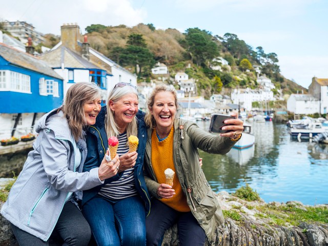 Group of travelers eating ice cream and taking selfie