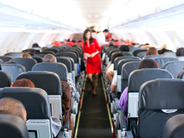 Flight attendant walking through aircraft aisle